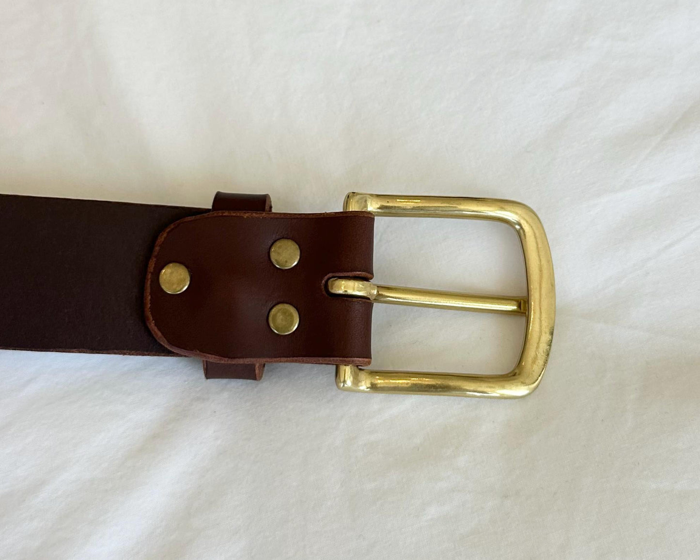 Brown leather belt with a gold buckle on a white background