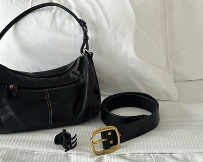 Black handbag and belt on a white bed