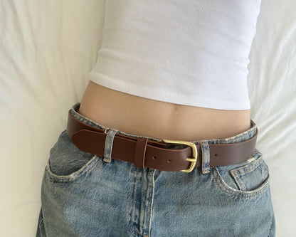 Person wearing a brown belt with a classic gold buckle.