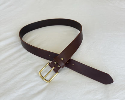 Brown leather belt with a gold buckle on a white background