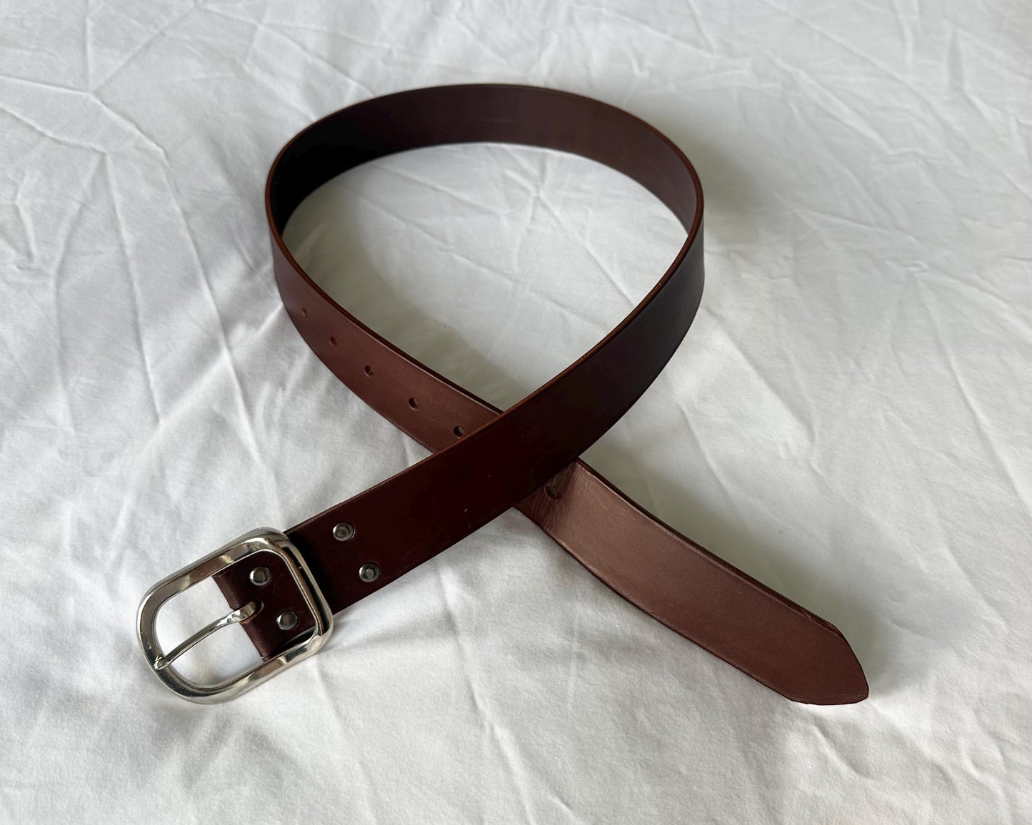 Brown leather belt with silver buckle on a white background