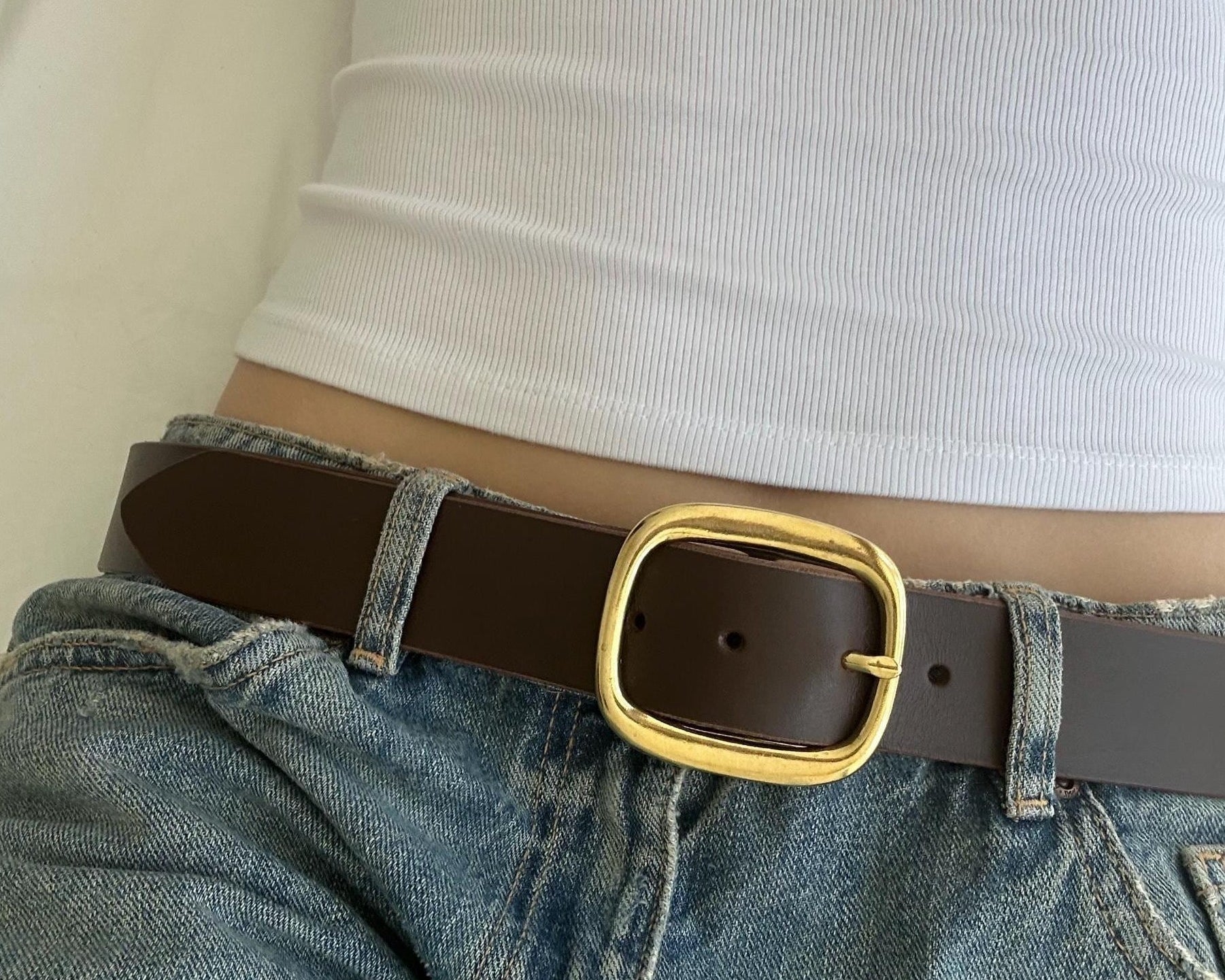 Person wearing a brown belt with a gold, statement buckle.