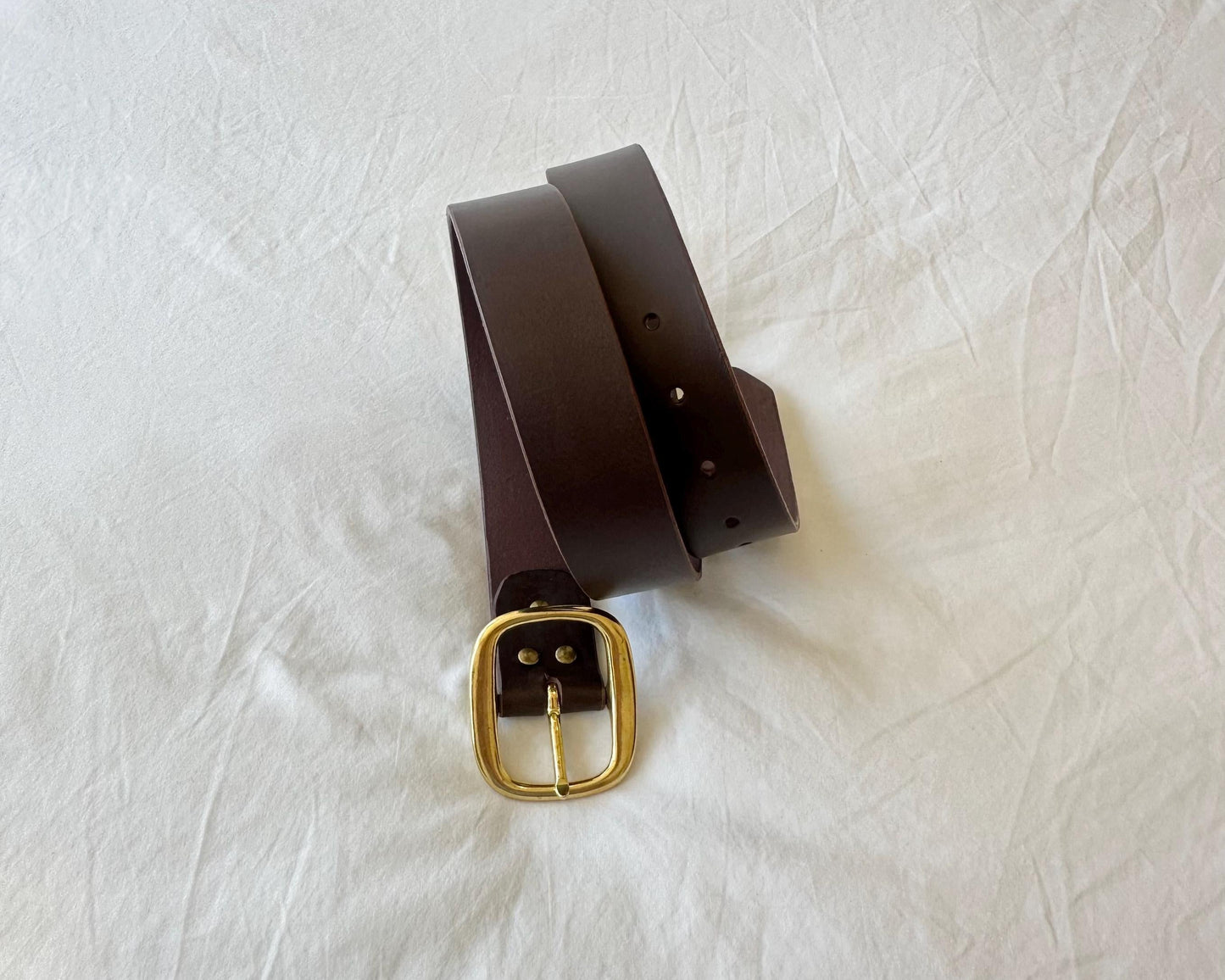 Brown leather belt with a gold buckle on a white background